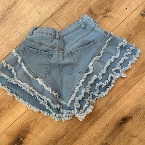 Small sized blue Jean shorts with frayed ruffle accents.